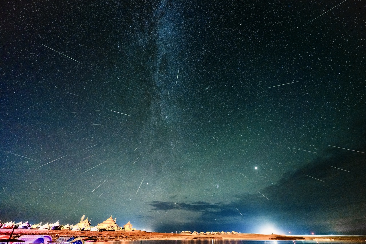 Nomad camp illuminated under a meteor shower.