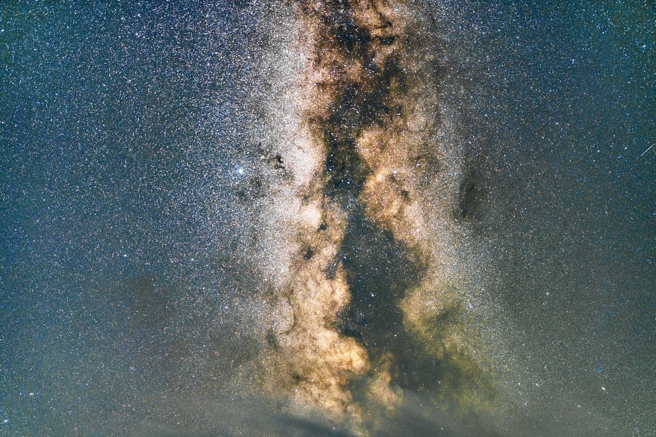 Vertical Milky Way pillar rising over plateau clouds.