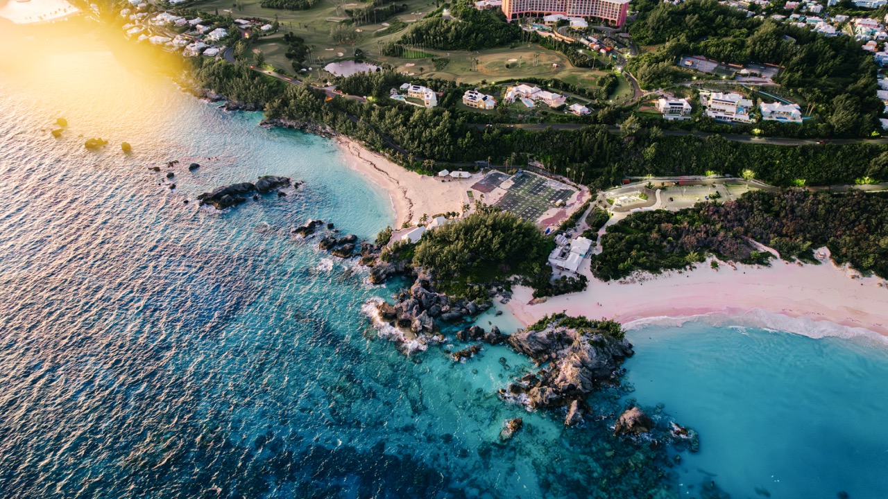 Drone shot of Bermuda's Horseshoe Bay pink sand meeting turquoise surf.