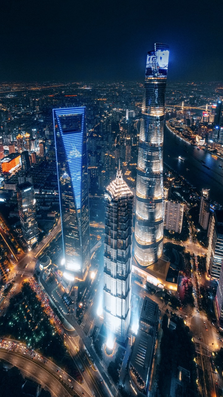 Drone shot 600 meters above Shanghai's trio of towers glowing at night.
