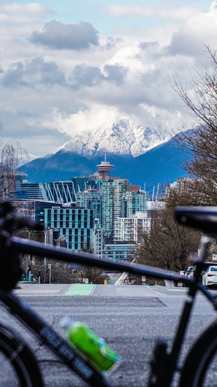 Rental bike paused along Vancouver's seawall with the TV tower and snow peaks beyond.